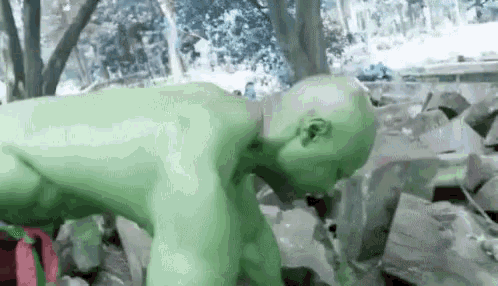 a man in a green costume is crawling through a pile of rocks .