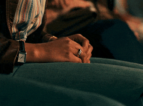 a person wearing a watch and a ring holds their hands together
