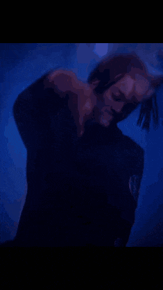 a man with dreadlocks is standing in front of a blue light