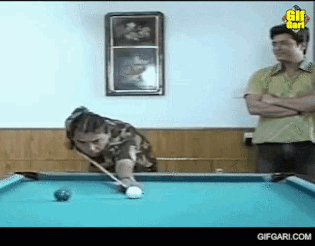 a man is playing pool in a room with gifgari.com written on the bottom of the screen