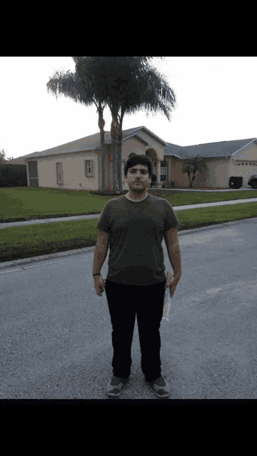 a man standing in front of a house holding a bottle