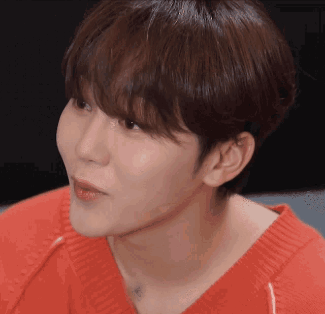 a close up of a person 's face with a red shirt on