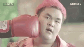 a man with red hair is wearing red boxing gloves and getting a punch in the face .