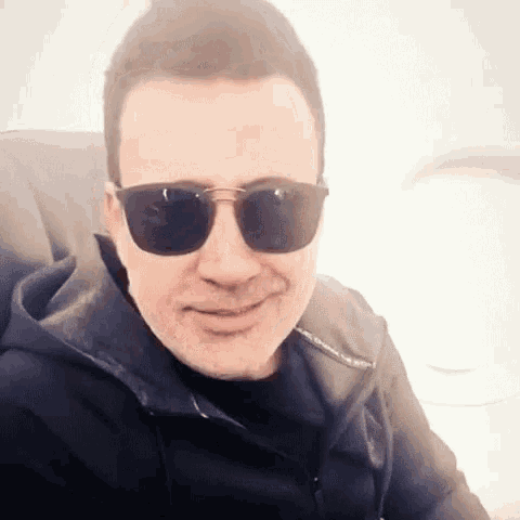 a man wearing sunglasses and a porsche jacket