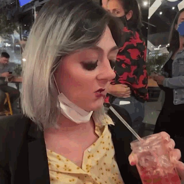 a woman wearing a face mask is drinking from a mason jar with a straw