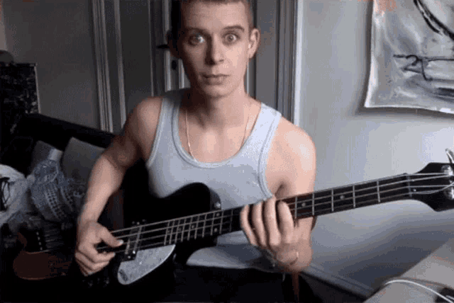 a man in a tank top is playing a guitar