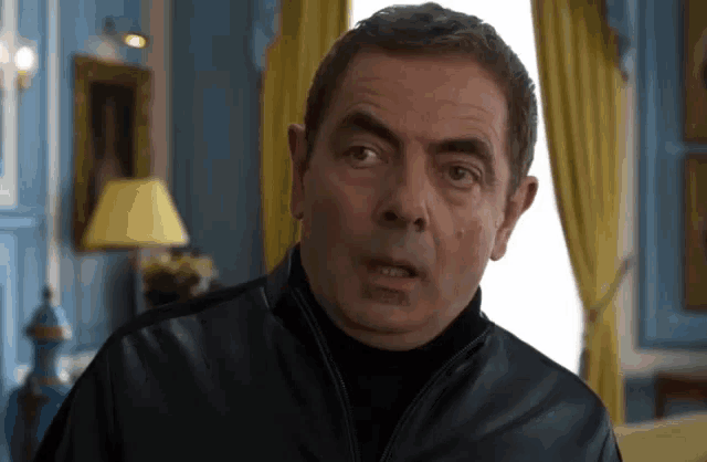 a man in a black leather jacket is looking at the camera