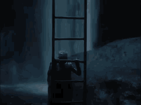 a man is climbing a ladder into a waterfall at night .