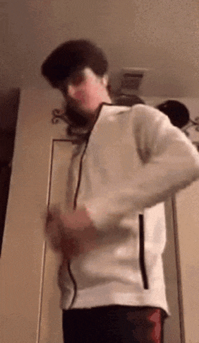 a man in a white jacket is standing in a room .
