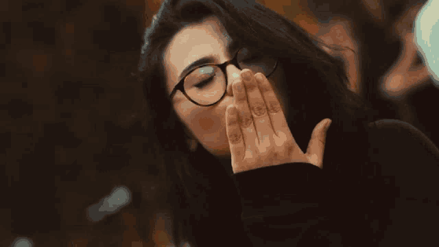 a woman wearing glasses is blowing a kiss at the camera