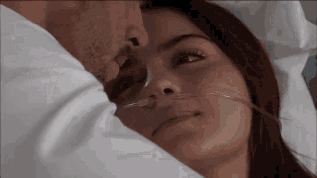 a man and a woman are laying in a hospital bed with oxygen tubes in their noses