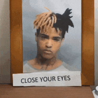 a picture of a man with dreadlocks has a sign that says close your eyes