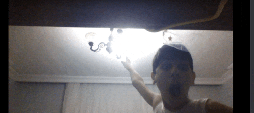 a man in a white tank top is pointing up at a chandelier