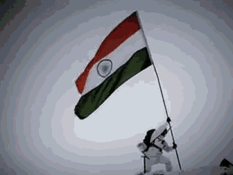 a man is holding a flag on top of a mountain .