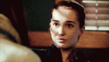 a close up of a woman 's face in a dark room with a window behind her .