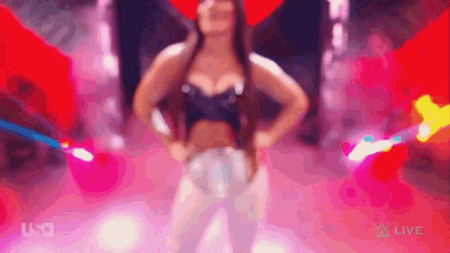 a woman in a black top and white pants is dancing in a pink and red room .