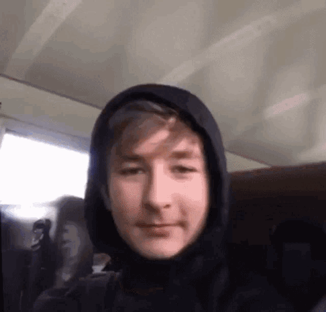 a young man wearing a hooded jacket is taking a picture of himself .