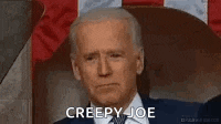 a man in a suit and tie is sitting in a chair and smiling with the words creepy joe written on his face .