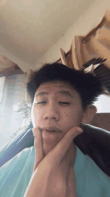 a young man in a blue shirt is making a funny face