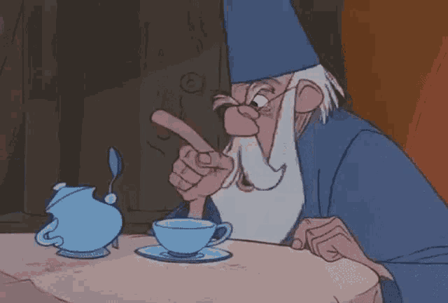 a cartoon wizard is sitting at a table with a cup of tea