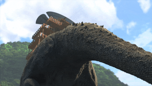 a close up of a dinosaur 's tail with a building in the background and a blue sky