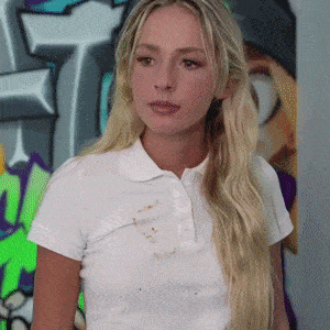 a woman wearing a white polo shirt is standing in front of a graffiti wall