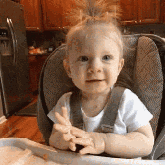 a baby is sitting in a high chair and making a face