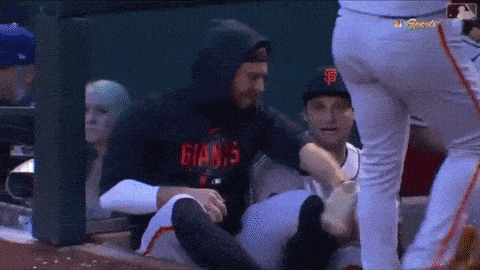 a baseball player wearing a giants shirt is being helped off the field