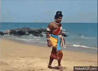 a man in a costume is walking on a beach near the ocean