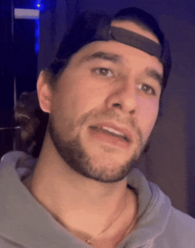 a man with a beard wearing a baseball cap and a necklace