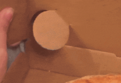a close up of a person 's hand holding a pink object in a cardboard box
