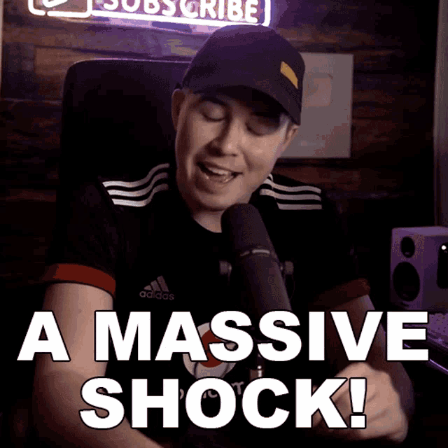 a man sitting in front of a microphone with the words " a massive shock " below him