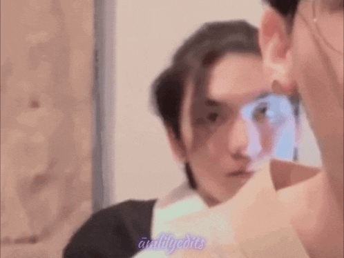 a close up of a man looking at himself in the mirror .