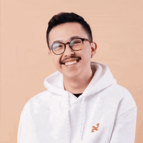 a man wearing glasses and a white hoodie laughs