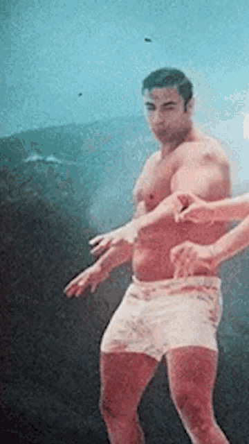 a shirtless man in white shorts is being touched by another person