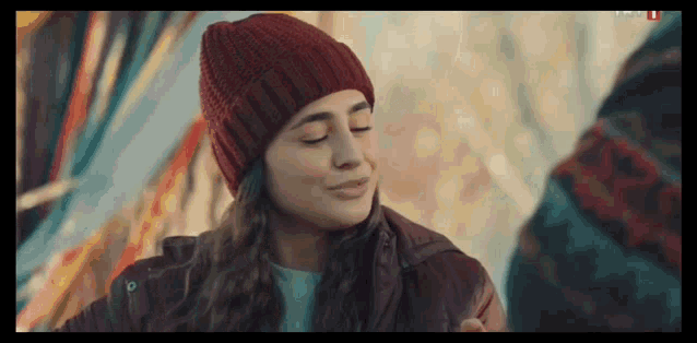 a woman wearing a red hat and a jacket is smiling