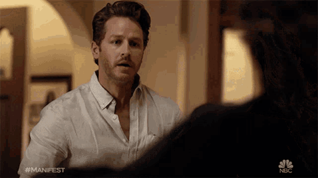 a man in a white shirt is talking to a woman in a nbc show