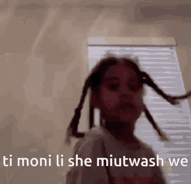 a little girl with pigtails is standing in front of a window and says ti moni li she miutwash we