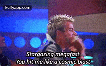 a man with a mohawk is singing into a microphone while another man looks on .