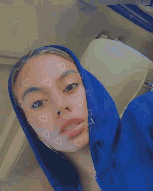 a woman wearing a blue hoodie with hearts on her face .