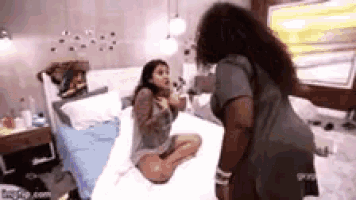 two women are standing next to each other in a bedroom .