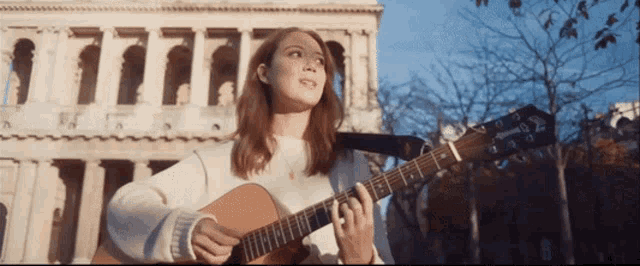 a woman playing a guitar in front of a building that says ' yamaha ' on it