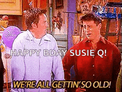 two men are standing next to each other in a kitchen with balloons in the background .