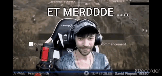a man wearing headphones and a hat is sitting in front of a microphone and says et merdde
