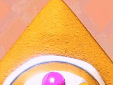 a close up of a donut with pink and yellow balls on top
