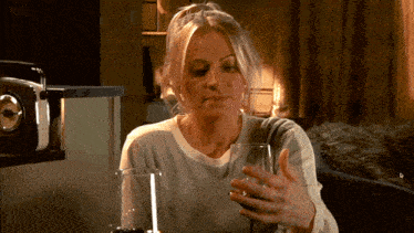 a woman sits at a table with a glass of wine in her hand