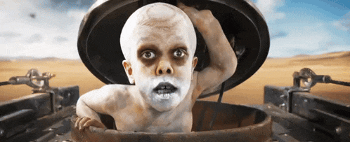 a child with white paint on his face is sticking his head out of a container