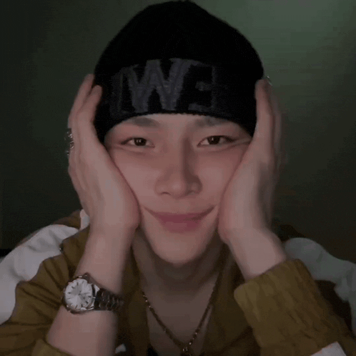 a man wearing a watch and a black beanie with the word we on it