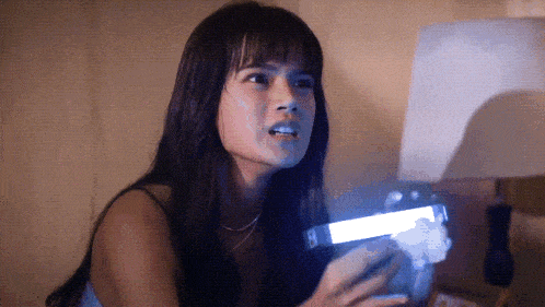 a woman holding a flashlight with the letter h visible on it