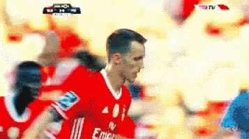 a soccer player wearing a red jersey with emirates on the front